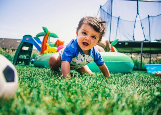 boy in blue and white crew neck t-shirt sitting on green grass field during daytime